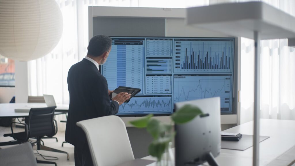 Professional in suit analyzing financial data on screens in a modern office setting