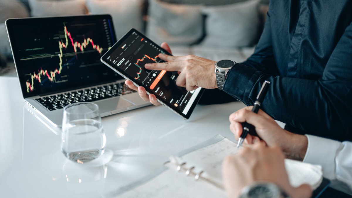Professionals analyzing financial data on a tablet and laptop in an office setting