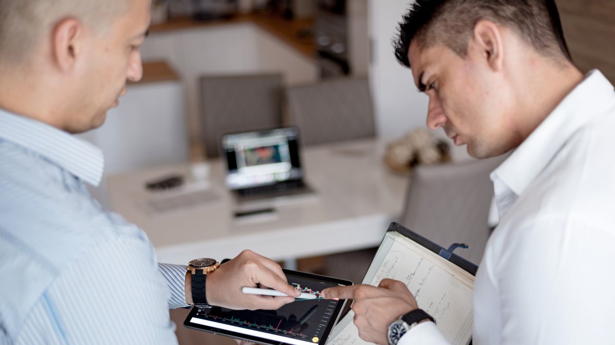 Two professionals reviewing financial charts on a tablet during a business meeting